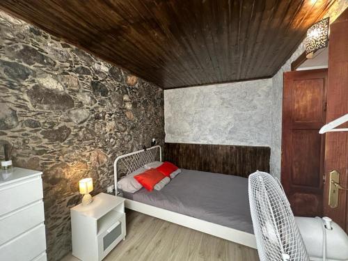 a bedroom with a bed and a stone wall at Casa Álamo Agaete in Agaete