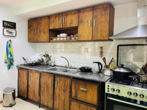 een keuken met houten kasten, een wastafel en een fornuis bij Guest House OLD WALL in Lagodekhi
