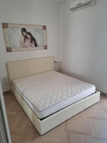 un letto bianco in una stanza con una foto sul muro di Appartamento Grandi a Peschici