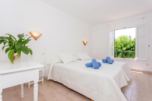 a white bedroom with two beds and a window at Cala'n Blanes Park 228 in Cala en Blanes