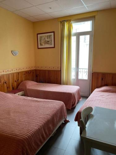 une chambre d'hôtel avec trois lits et une fenêtre dans l'établissement Notre Dame AUXILIATRICE, à Lourdes
