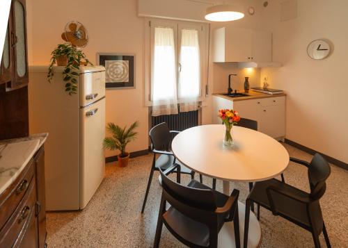 una cucina con tavolo, sedie e frigorifero di Ca' Glera: Vintage Charm Apartament a Revine Lago