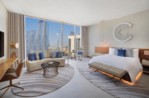 The St. Regis Downtown Dubai في دبي: غرفة نوم مع سرير مزدوج كبير وأريكة