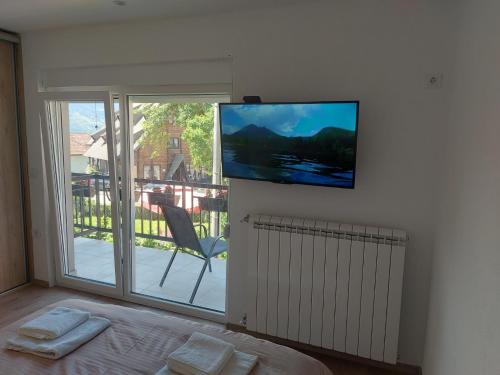 Habitación con TV en la pared, cama y ventana. en Rooms Lida & Friendly home en Plav