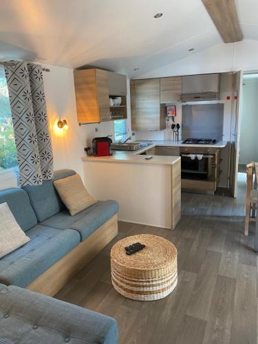 un salon avec un canapé bleu et une cuisine dans l'établissement mobilhome la palmyre bonne anse plage, aux Mathes