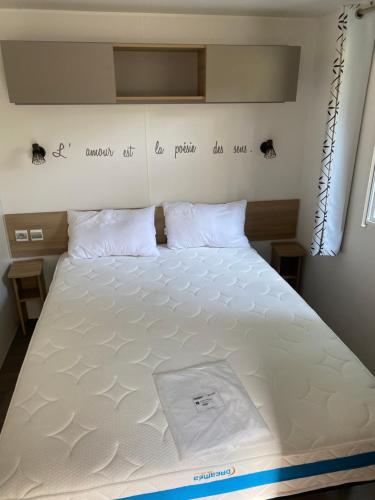 a large white bed in a small room at mobilhome la palmyre bonne anse plage in Les Mathes