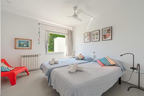 a bedroom with two beds and a red chair at Es Forti 52 in Santanyi