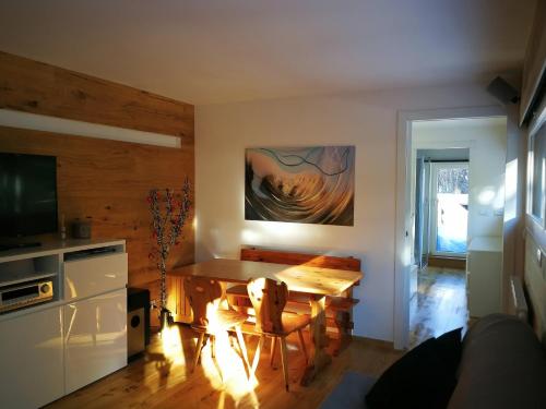 ein Wohnzimmer mit einem Esstisch und einem TV in der Unterkunft Antermoia Suite - servizio navetta, sala giochi e bici incluse in Mazzin