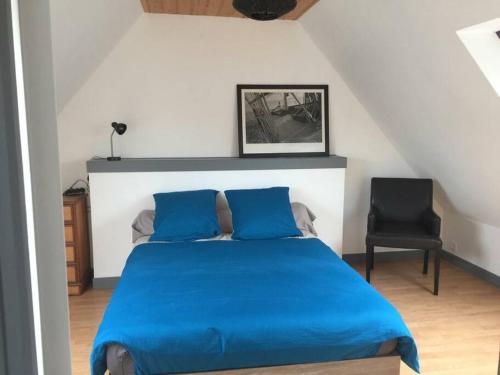 - une chambre avec un lit bleu et une chaise noire dans l'établissement Longère Bretonne près du GR34, à Trébeurden