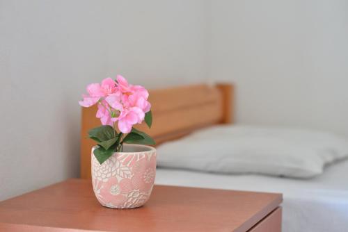 un fiore rosa in un vaso seduto su un tavolo di Studio's Stelios a Leptokarya