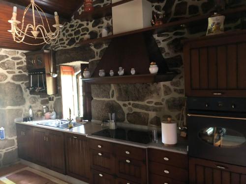 a kitchen with a sink and a stone wall at QUINTA DONA MANUELA in Formariz