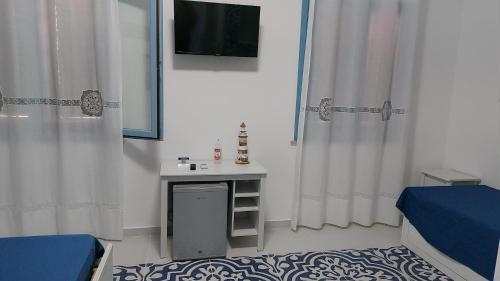 マカリにあるBenvenuti al Sud B&Bのテレビ、テーブル、カーテンが備わる客室です。