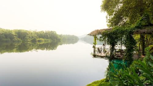a house on the side of a large lake at Munkudil Ayurveda & Yoga Retreat in Kuttampuzha