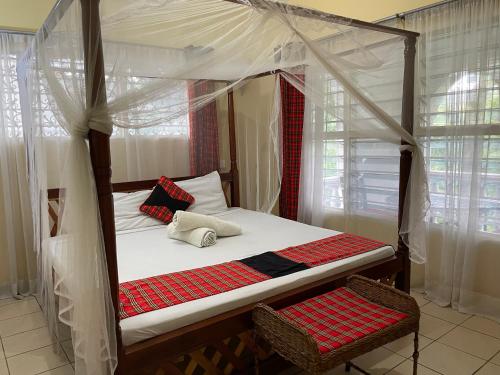 a bedroom with a canopy bed with two chairs at Maasai Resort in Mombasa