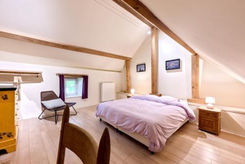 een slaapkamer met een bed en een stoel in een kamer bij Le gîte de Froidefontaine in Havelange