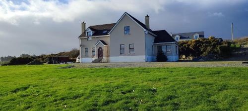une maison blanche sur une colline avec un champ vert dans l'établissement Tullyally's View, à Red Castle