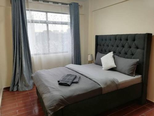 um quarto com uma cama grande e uma janela grande em Serene apartment in the suburbs em Nairobi