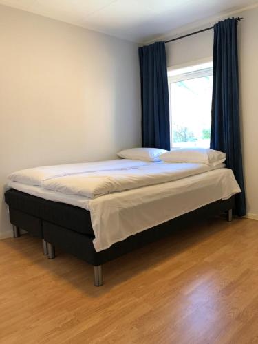 un letto in una camera da letto con finestra e tende blu di Modern apartment with an amazing seaview a Ballstad