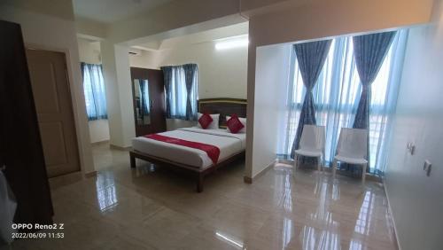 Un dormitorio con una cama y dos sillas blancas. en Hotel Amulya Relax Inn, en Bangalore