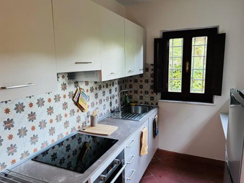 cocina con armarios blancos, fregadero y ventana en La Casina di Susy, en Seravezza