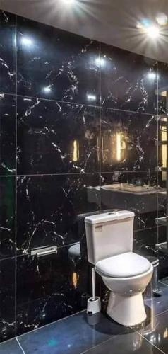 a bathroom with a toilet and a black tiled wall at TMD COMFORTABLE TRANSIENT HOUSE IN STO.TOMAS BATANGAS (UNIT 1) in San Felix