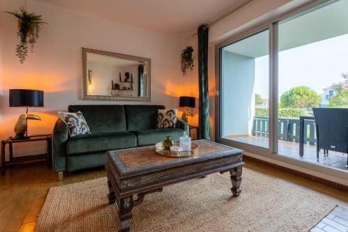 un salon avec un canapé vert et une table dans l'établissement Studio plage de Capbreton avec terrasse, à Capbreton
