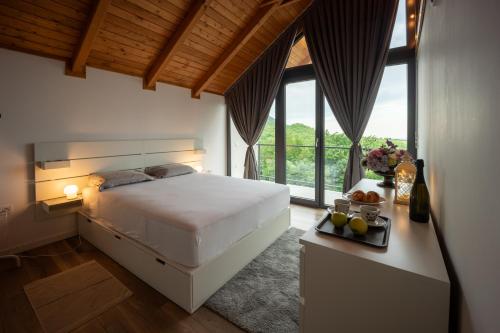 a bedroom with a white bed and a large window at Copanjek Country House in Plešivica
