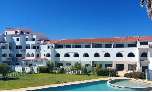 een groot wit gebouw met een zwembad ervoor bij Casa Papillon in Sagres