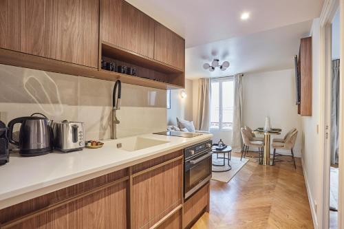 a kitchen with wooden cabinets and a sink and a table at Apart hotel Centre de Paris by Studio prestige in Paris