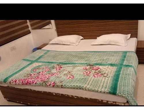 - un lit avec une couverture verte et des fleurs dans l'établissement Hotel Shivaahana Residency, Katra, à Katra
