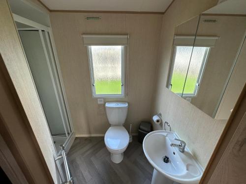 ein Badezimmer mit einem WC, einem Waschbecken und einem Spiegel in der Unterkunft 27 Rickardos Holiday Lets 3-Bed Caravan near Mablethorpe in Saltfleet