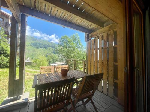 une terrasse couverte avec une table et des chaises en bois. dans l'établissement Appart 250m des pistes et parking couvert privatif, à Orcières