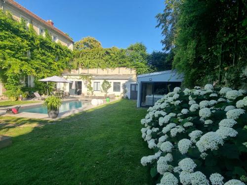 a hedge of white flowers in a yard at Demeure Les Aiglons, Chambres d'hôtes & Spa in Fontainebleau