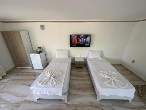 two beds in a room with a tv on the wall at Kiriş Garden Hotel in Kemer