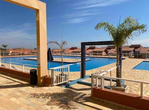 - une piscine avec un palmier à côté d'un bâtiment dans l'établissement Catarina Chalé - Cond Clube, à Mairinque