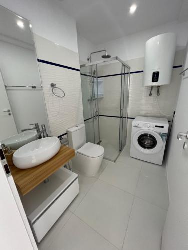a bathroom with a toilet sink and a washing machine at Oxygen Residence Neptun in Neptun