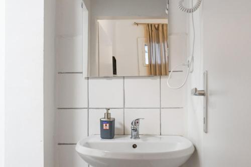 La salle de bains blanche est pourvue d'un lavabo et d'un miroir. dans l'établissement Affordable 2BR Apt- Connected to the whole city, à Vienne