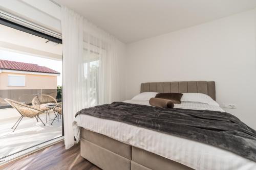 a bedroom with a large bed and a balcony at Villa Nelly in Privlaka