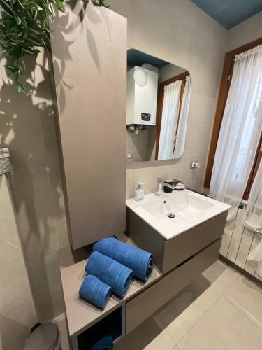 bagno con lavandino, specchio e asciugamani blu di Casa Fiorenza a Chioggia