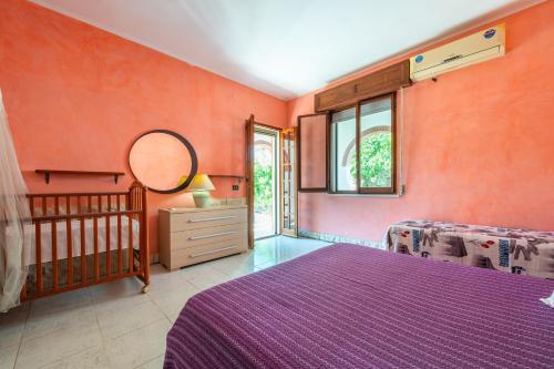 Schlafzimmer mit orangefarbenen Wänden, einem Bett und einem Spiegel in der Unterkunft Villetta Sant'andrea in Quartu SantʼElena