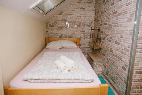 ein kleines Schlafzimmer mit einem Bett in einer Ziegelwand in der Unterkunft Sobe Tatjana in Palić