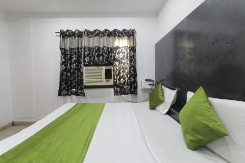 a bedroom with a bed with green pillows and a window at Hotel Dayal in Lucknow
