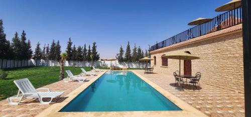 a swimming pool with chairs and umbrellas at Auberge Dar Laazouzi 