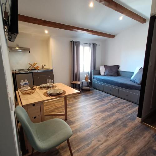 un salon avec une table et un canapé bleu dans l'établissement Studio LA MOUTONNE tt équipé 20 m2 10mn plages- hyeres - TRES CALME-, à La Crau