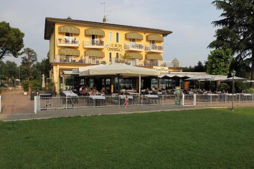 un edificio amarillo con gente sentada en mesas delante de él en Hotel Campanello, en Castelnuovo del Garda
