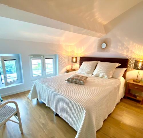 een slaapkamer met een wit bed en 2 ramen bij La Dormance in Beaune