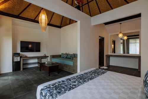 a bedroom with a bed and a desk and a television at Ubud Dedari Villas in Ubud