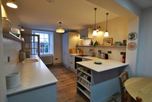 une cuisine avec des comptoirs blancs et une table à l'intérieur dans l'établissement Sea Holly Cottage- coastal retreat Pittenweem, à Pittenweem