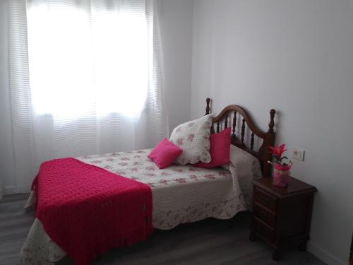 una camera da letto con un letto con cuscini rosa e una finestra di Aires do mar a O Grove