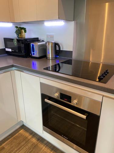 a kitchen with a stove and a microwave at Stunning & Luxury Flat in Sutton